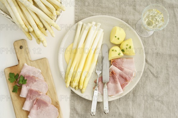 Traditional German dish with white asparagus, boiled ham, hollandaise sauce and potatoes, served on