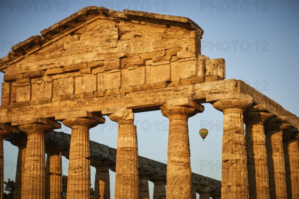Sunset behind ancient columns of a temple with a clear sky, summer evening mood in Paestum, ancient