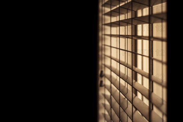 Horizontal shot of venetian blinds creating a moody and noir inspired atmosphere with light