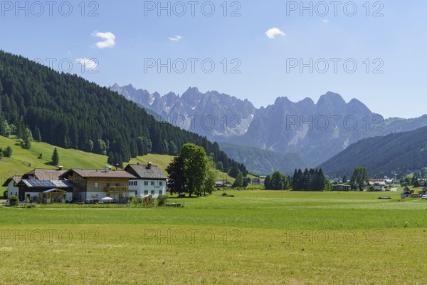 A small village surrounded by green meadows and mountains under a clear blue sky, Gosau, Austria,