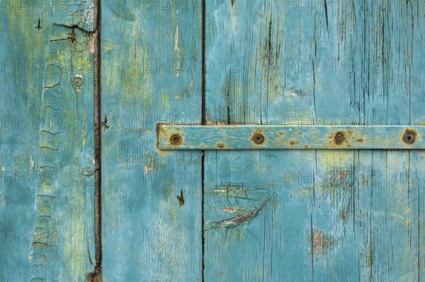 Old wooden door with peeling paint and iron fittings, texture, background, Montenegro, Balkans,