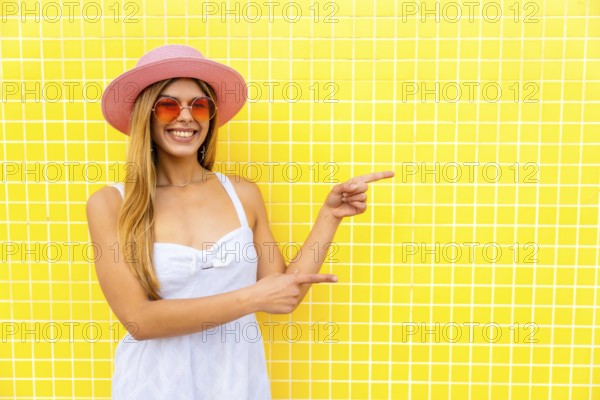 Fashionable woman indicating empty space on vibrant yellow background, ideal for showcasing