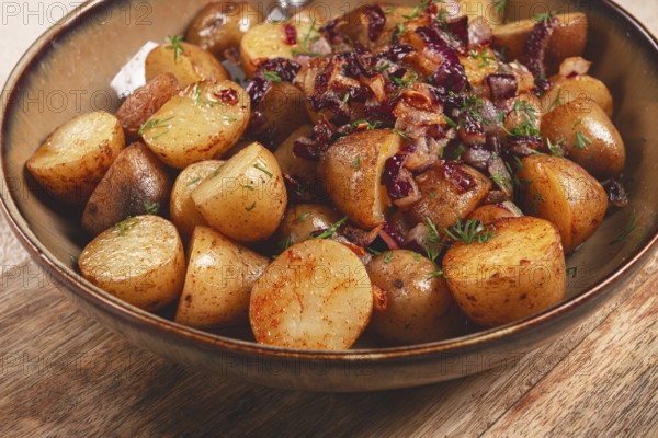 A bowl filled with golden roasted potatoes seasoned with spices and garnished with caramelized