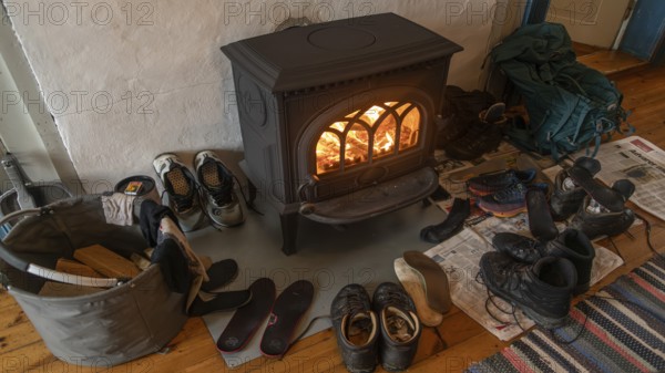 Drying wet hiking boots in front of a burning wood-burning stove, Fokstugu farm, Fjellstue,