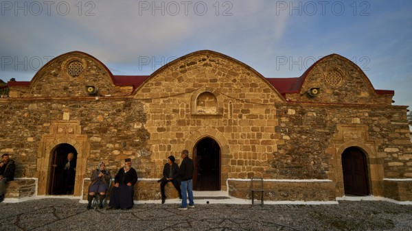 Old stone building in the evening light, people standing in front of the historic facade, Easter