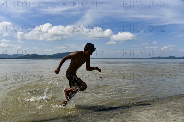 Boys jump in the Brahmaputra river during an a hot summer day in Guwahati, india on July 11, 2022