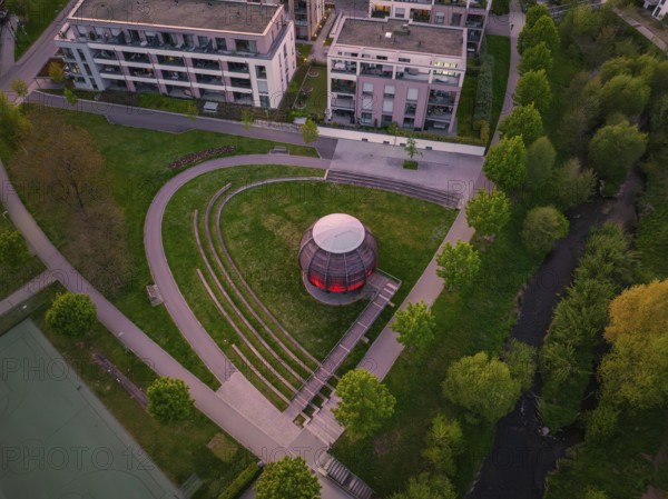 Aerial view of a modern wooden construction in the park with trees and surrounding buildings at