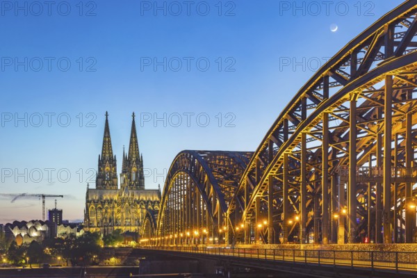 Cologne Cathedral, illuminated in the evening. Hohenzollern Bridge, railway bridge over the Rhine.