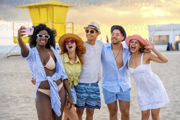 Group of multi ethnic friends taking a selfie on the beach in miami, florida, with lifeguard tower