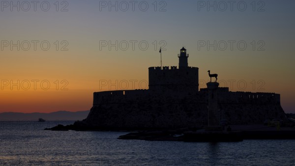 Fortress by the sea silhouetted against a colourful sunrise, dawn, Fort of Saint Nikolaos, Mandraki
