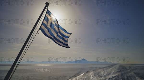 Greek flag in the foreground, over a widening sea under a blue sky, crossing Rhodes to Symi, ferry,