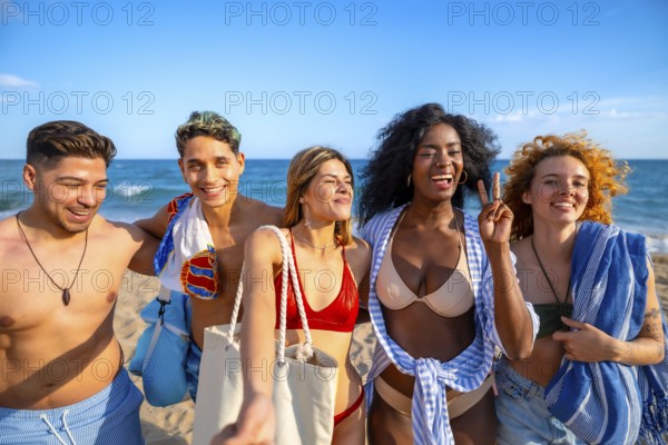 Group of multi ethnic friends enjoying a sunny day at the beach, capturing joyful moments while