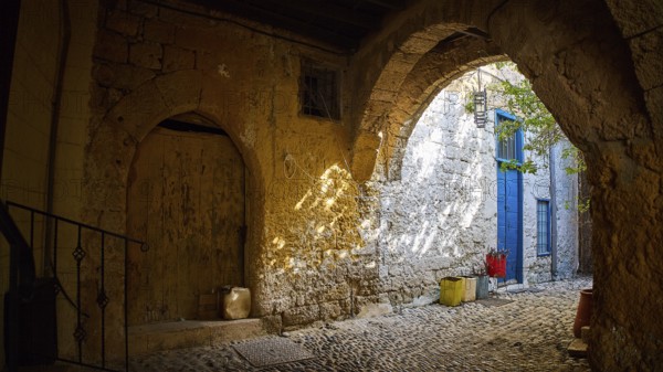 Weathered stone arcade with rays of light falling through an old archway, Rhodes Old Town, Rhodes,