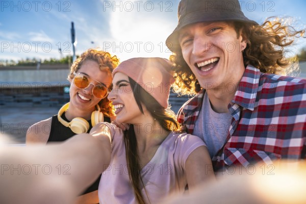 Three cheerful young friends taking a selfie outdoors, soaking up the sun and enjoying a vibrant