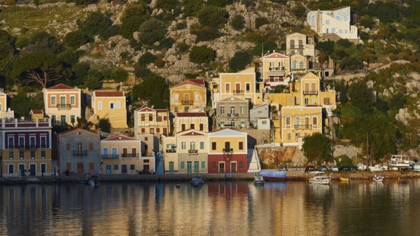 Colourful buildings along the water with some boats on the shore, Mediterranean scenery, Symi town,
