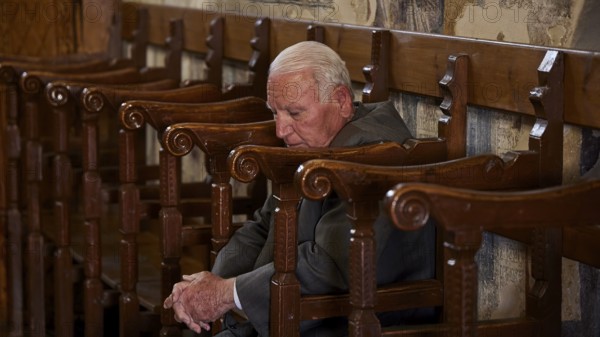 An elderly man leans back in a chair, his eyes closed as if he is sleeping, Easter 2025, Church of