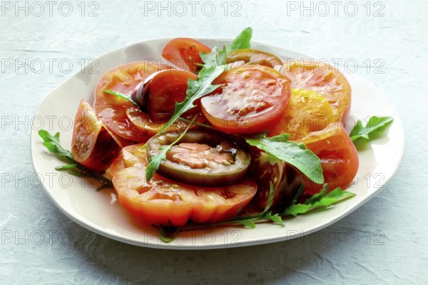Fresh tomato and rocket salad. A variety of tomatoes of different sorts with arugula leaves.