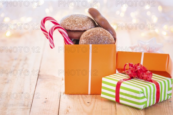 Ton of colorful gifts, one opened full with gingerbread and Xmas candies, laid on a wooden