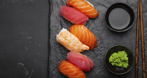 Traditional Japanese sushi with soy sauce, wasabi, chopsticks top view on dark black rustic slate.