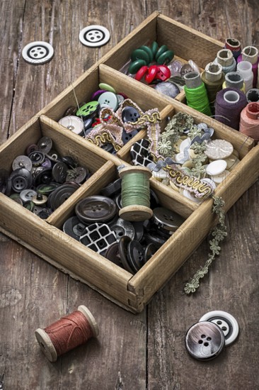 Old wooden box with thread and buttons for needlework in vintage style