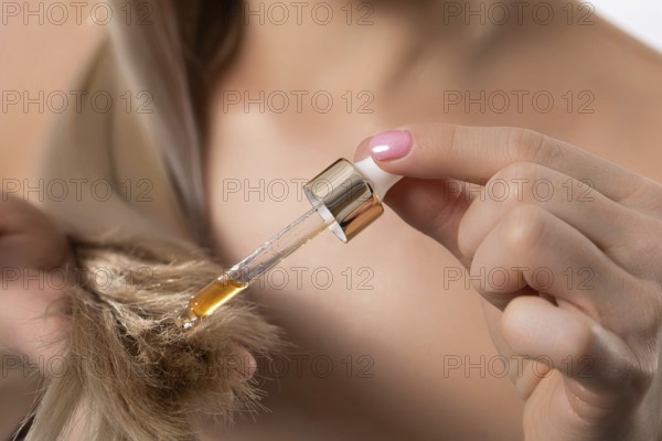 A stylish and fashionable woman carefully applying nourishing hair oil to achieve optimal hydration