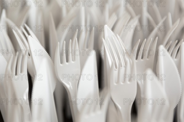 White plastic forks and knifes are seen stacked. Most disposable plastic utensils are made of