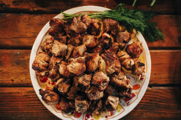 Shish kebab on skewers in a plate on a wooden table