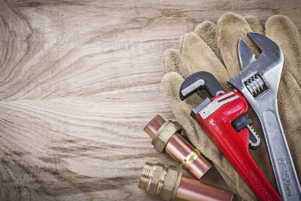 Safety gloves copper water pipe wrench hose nipples adjustable spanner on wooden board plumbing
