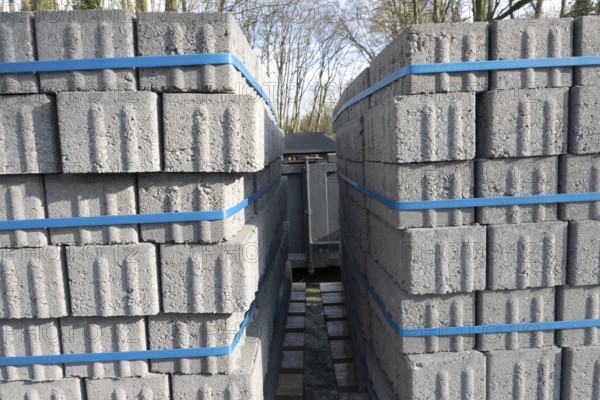 Concrete bricks, secured with blue straps, are being transported on a truck, ready for construction
