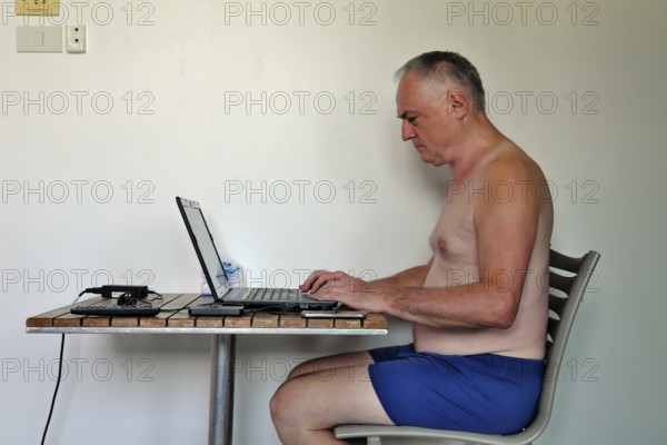 Businessman, freelancer, 60 plus on holiday working with laptop and mobile phone, Pattaya,