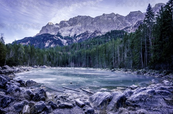 Winter scenery with an alpine frozen lake surrounded by the German Alps, near the municipality