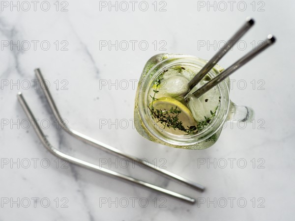 Metal drinking straws and cold drink in glass mason jar on white marble background. Top view or