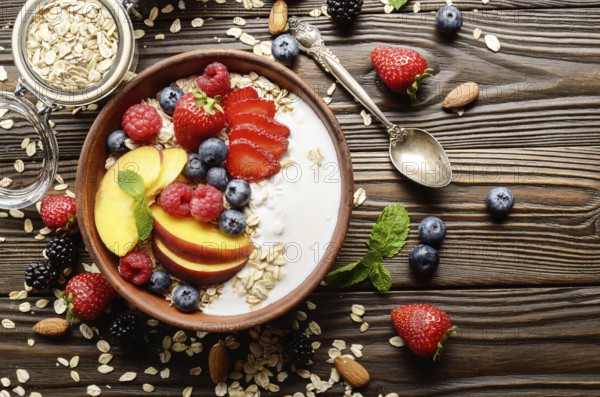 Flat lay of fruit healthy muesli with peaches strawberry almonds and blackberry in clay dish with