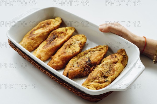 Female hand holding a tray with torrijas, a typical Spanish sweet fried toasts of sliced bread