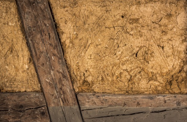 Clay house wall, with details on the wooden beams and the mixture of mud and straw, perfect as