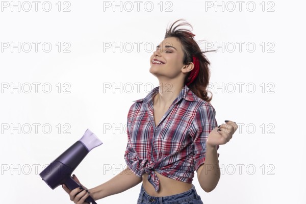 A young woman is playfully drying her hair while exuding both confidence and pure joy in her
