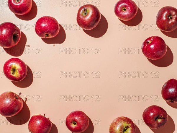 Red apples on orange or coral pink background with copy space for text or design in center.