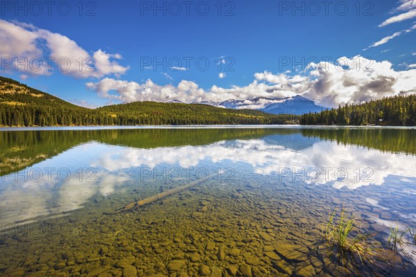 Clear water Pyramid Lake reflects the clouds and pine forests on shore. Frosty morning in the Rocky