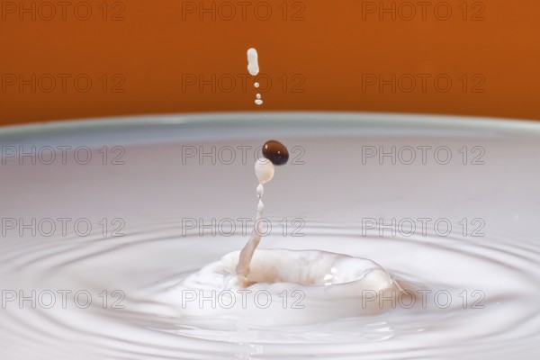 A drop with a splash in an orange environment creates dynamic fluid movement, water droplets,