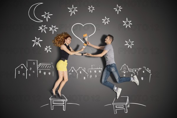 Happy valentines love story concept of a romantic couple standing on a stool and painting a heart