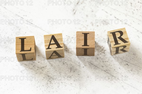 Four wooden cubes with letters LAIR (meaning Listen Acknowledge Identify Reverse) on white working