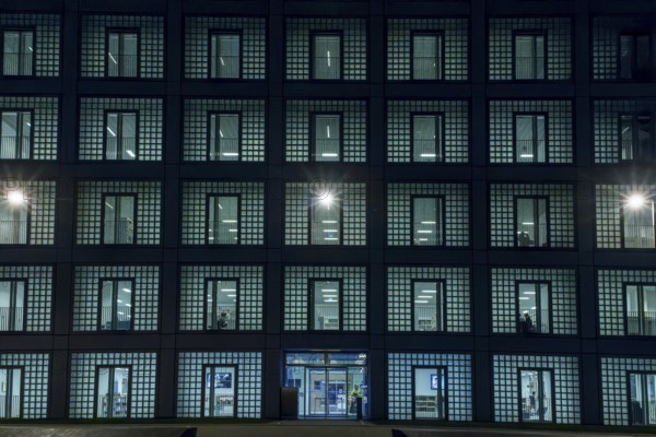 Night shot of the façade with entrance door and countless windows of the cube-shaped city library