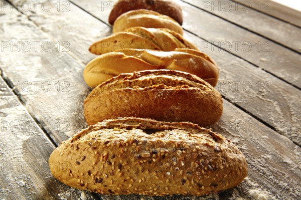 Breads varied in a row on rustic wood table with wheat flour