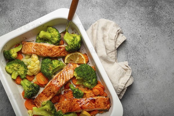 Top view of healthy baked fish salmon steaks, broccoli, cauliflower, carrot in casserole dish on