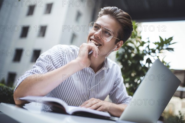 Happy handsome businessman mixes his break and job outdoors, businessman with headphones write some