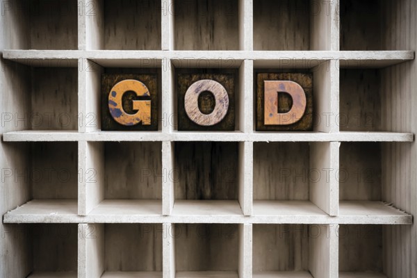 The word GOD written in vintage ink stained wooden letterpress type in a partitioned printer's