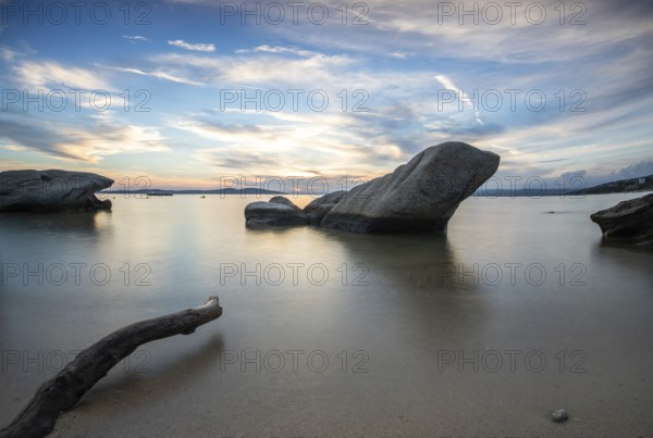 View through rocks on a sandy beach into the sunset. Landscape shot with view to the horizon over