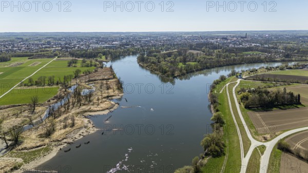 View of a river (Danube) with riverside vegetation, neighbouring fields and a town in the distance,
