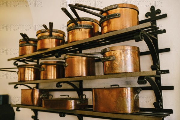 Pots, ladles, tray and saucepan made of copper, in various sizes, on massive metal shelves, fixed