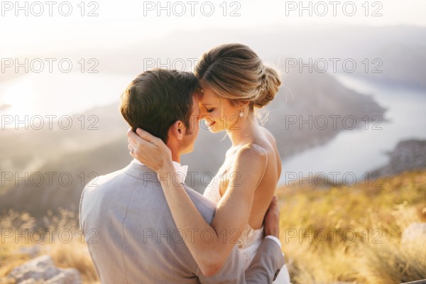 The bride and groom sitting on the top of Mount Lovcen overlooking the Bay of Kotor, smiling and